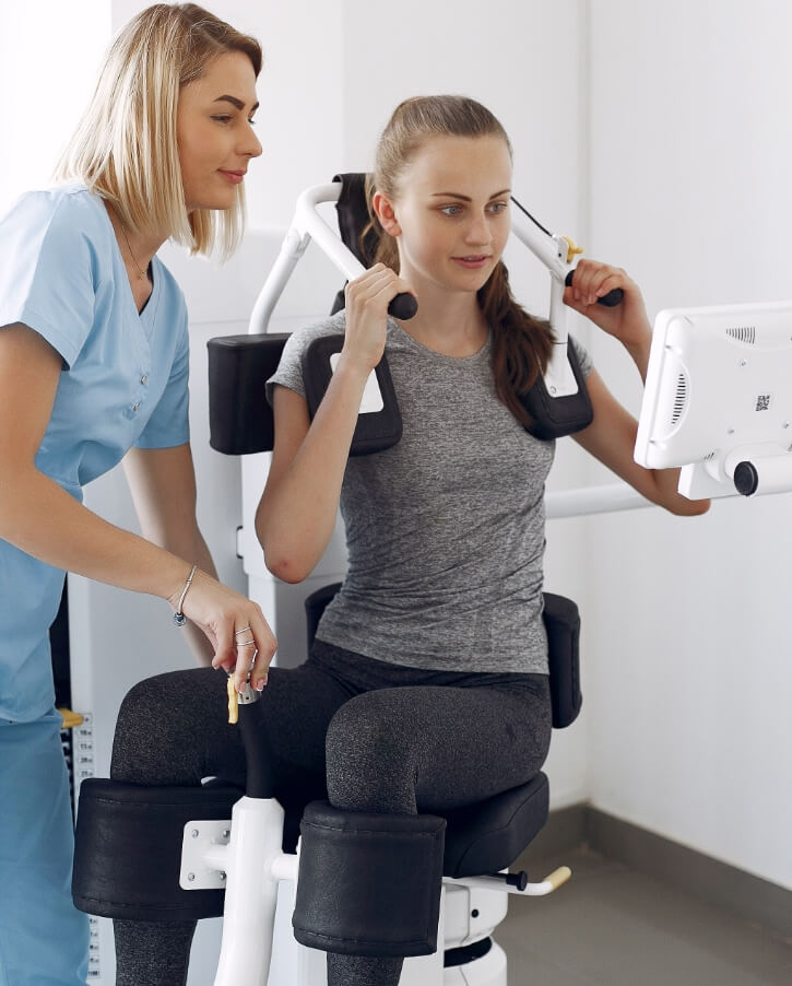 Physiotherapist supervising a patient during a strength exercise on gym equipment at Farnham Physiotherapy & Sports Clinic